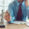 Attorney talking on mobile device and playing with Justice scale in law office, selective focus on statue of Lady Justice